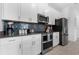 Modern kitchen with stainless steel appliances, gray countertops, white cabinets, and stylish backsplash at 4403 Scene Ln, Kissimmee, FL 34746