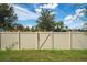 Fenced backyard with a gate, leading to a playground surrounded by lush greenery at 454 Sunfish Dr, Winter Haven, FL 33881