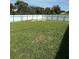 A large backyard with lush green grass is enclosed by a white fence and surrounded by trees at 506 Myakka Pl, Kissimmee, FL 34759