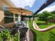 Inviting backyard patio with comfortable seating, a hammock, a pergola, and a well-maintained lawn, great for gatherings at 1456 Sourwood Dr, Ocoee, FL 34761