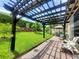 Beautifully landscaped backyard with a pergola-covered patio and lush green grass, perfect for outdoor entertaining at 1456 Sourwood Dr, Ocoee, FL 34761
