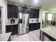 Modern kitchen features stainless steel appliances, dark cabinetry, granite countertops, and light wood flooring at 1456 Sourwood Dr, Ocoee, FL 34761