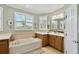 Bright bathroom featuring a soaking tub, double vanity, and plenty of natural light from multiple windows at 324 Sorrento Rd, Poinciana, FL 34759