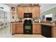 Cozy kitchen with wood cabinets, black appliances, and granite-style counters at 324 Sorrento Rd, Poinciana, FL 34759