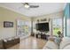 Bright living room featuring large windows with shutters and a view of the lush backyard at 324 Sorrento Rd, Poinciana, FL 34759
