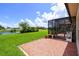 A tiled patio with furniture looks out to a green yard with a pond at 324 Sorrento Rd, Poinciana, FL 34759