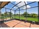 Screened lanai with geometric tiled floors overlooking lush green yard and pond at 324 Sorrento Rd, Poinciana, FL 34759