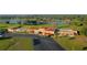 Aerial view of the clubhouse with a red tile roof and a large parking lot, and part of a golf course in the background at 4331 Valencia Dr, Indian Lake Estates, FL 33855