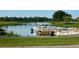 View of community boat dock featuring several pontoon boats on the water, with green trees and grass in the background at 4331 Valencia Dr, Indian Lake Estates, FL 33855