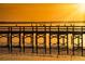 Tranquil lake pier at sunset, with birds perched on the railing and a golden sky reflecting on the water at 4331 Valencia Dr, Indian Lake Estates, FL 33855