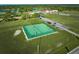 Aerial view of a community tennis court surrounded by lush green lawns, with a parking lot and a pond in the background at 4331 Valencia Dr, Indian Lake Estates, FL 33855