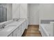 Bright bathroom with double sinks, quartz countertops, tile surround shower, and wood-look flooring at 4711 Sw 136Th Pl, Ocala, FL 34473
