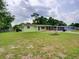 Well-maintained single-story home featuring a green lawn, mature trees, and a screened patio at 10161 Sw 87Th Ter, Ocala, FL 34481
