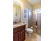 Bathroom with granite countertops, wooden cabinets, toilet, and tiled shower at 8339 Bridgeport Bay Cir, Mount Dora, FL 32757