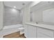 Bathroom features a tub-shower combo, white vanity with modern countertop and wood-look flooring at 14192 Sw 44Th Ct, Ocala, FL 34473