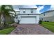 Two-story home featuring a brick driveway, white garage door, and neatly landscaped yard at 1564 Eucalyptus Way, Davenport, FL 33837