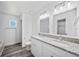Modern bathroom with double sinks, granite counters, and gray luxury vinyl plank flooring at 2700 Laguna Dr, Indian Lake Estates, FL 33855