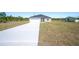 New single-Gathering home with a gray roof, white garage, and long concrete driveway at 2700 Laguna Dr, Indian Lake Estates, FL 33855