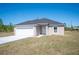 New single-Gathering home with a gray roof, white garage, and long concrete driveway at 2700 Laguna Dr, Indian Lake Estates, FL 33855