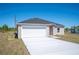 New single-Gathering home with a gray roof, white garage, and long concrete driveway at 2700 Laguna Dr, Indian Lake Estates, FL 33855