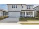 Two-story home with gray siding, a light green door, and a two-car garage at 4390 Sw 84Th Street Rd, Ocala, FL 34476