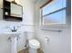 Well-lit bathroom with a pedestal sink, toilet, and a window for natural light at 1803 Fredricksburg Ave, Lakeland, FL 33803
