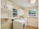 Functional laundry room featuring a stacked washer and dryer, upper cabinets, and natural light from two windows at 3603 Cr 626N, Bushnell, FL 33513