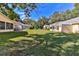Spacious backyard featuring lush green grass and mature trees, with patio and sunroom additions to adjacent homes at 8872 Sw 92Nd Pl # E, Ocala, FL 34481