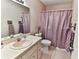This bathroom features a standard toilet, vanity with a single sink, neutral wallpaper, and a shower with a purple curtain at 8872 Sw 92Nd Pl # E, Ocala, FL 34481
