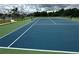 Blue and green tennis court with surrounding trees at 431 Bay Leaf Dr, Kissimmee, FL 34759