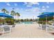 A luxurious community pool area with umbrellas, lounge chairs, tables, and palm trees for relaxation and enjoyment at 8311 Foster Dr, Davenport, FL 33896