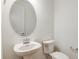 Elegant half bathroom with a modern pedestal sink and oval mirror at 4457 Sw 84Th Street Rd, Ocala, FL 34476