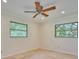 Light-filled, neutral bedroom with tile floors, ceiling fan and dual windows at 2771 Park Ave, Indian Lake Estates, FL 33855