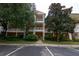 Multi-story condo building with white balconies and orange exterior, surrounded by mature trees at 308 New Providence # 308, Davenport, FL 33897