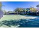 Well-maintained community tennis court with green surface, surrounding trees, and nearby buildings at 308 New Providence # 308, Davenport, FL 33897