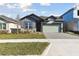 Two-story home with gray and green exterior, stone accents, and a paved driveway at 6075 Sacred Oak Ave, Mount Dora, FL 32757