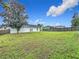 Sprawling backyard with a lush green lawn, mature trees, and a privacy fence at 7713 Manor Dr, Lakeland, FL 33810