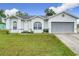 Charming single-story home with a well-manicured lawn, grey door, and a two-car garage at 7713 Manor Dr, Lakeland, FL 33810