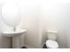 Stylish half bath features a pedestal sink, oval mirror and a white toilet at 13490 Leaping Water Way, Astatula, FL 34705