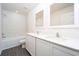 Bright bathroom featuring double sinks, white cabinets, quartz counters, and a tiled shower over tub at 13490 Leaping Water Way, Astatula, FL 34705