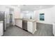 Kitchen island with sink, granite countertops, stainless steel appliances, and gray flooring at 13490 Leaping Water Way, Astatula, FL 34705