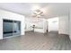 Bright open-plan living room with modern ceiling fan, gray flooring, and sliding glass doors at 13490 Leaping Water Way, Astatula, FL 34705