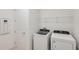 Bright laundry area featuring modern, front-load washer and dryer set with shelving and easy access to utility panel at 4432 Sw 84Th Street Rd, Ocala, FL 34476