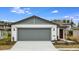 Inviting exterior of a single-story home with a gray garage door and landscaping at 5414 Sw 85Th Avenue Rd, Ocala, FL 34481