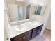 Bathroom with double sinks, marble countertops, dark wood cabinets, and large mirrors at 6855 Mossy Oak Ln, Lakeland, FL 33810