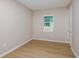 Neutral-toned bedroom with light wood flooring, a window providing natural light, and a white door at 5813 Sw 87Th Court Rd, Ocala, FL 34481