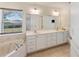 Bright bathroom featuring a double sink vanity, tiled floors, garden tub, and a large window with natural light at 4995 County Road 121D, Wildwood, FL 34785