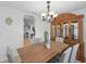Dining room with modern light fixture, long wooden table, six cushioned chairs, and a classic china cabinet at 4995 County Road 121D, Wildwood, FL 34785