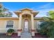 Front entrance with a decorative glass door and manicured landscaping at 4995 County Road 121D, Wildwood, FL 34785