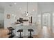 Open-concept kitchen with granite countertops, white cabinetry, stainless appliances, and bar seating at 4995 County Road 121D, Wildwood, FL 34785